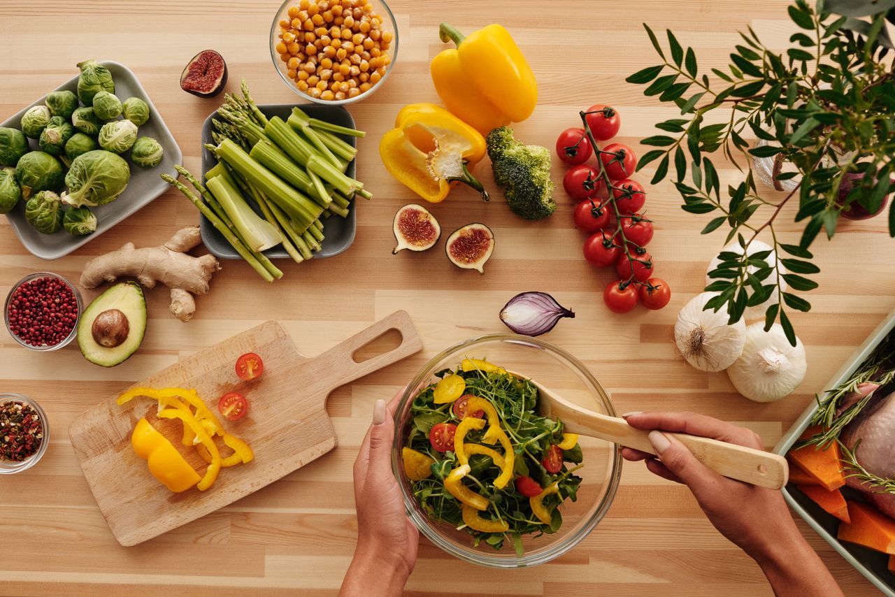 Home Top view of fresh vegetables and salad preparation on a wooden table, perfect for healthy eating concepts.