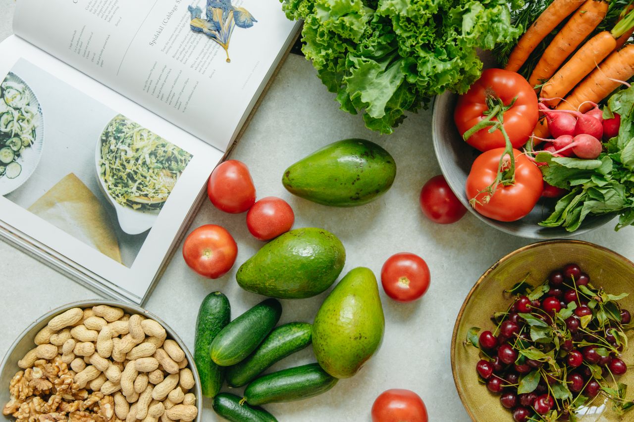 Home An appetizing display of fresh fruits and vegetables with a cookbook, perfect for healthy recipes.