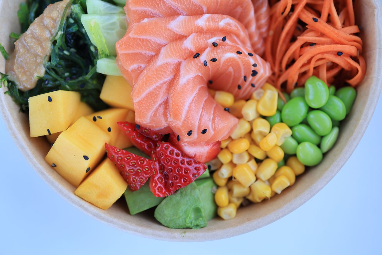 Colorful poke bowl featuring fresh salmon, vegetables, and fruits for a healthy meal.